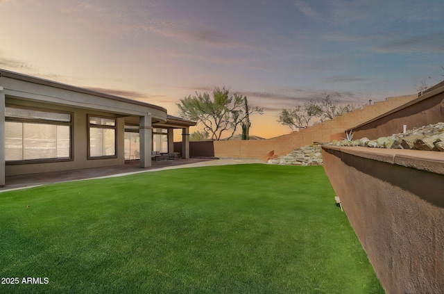 yard at dusk with a patio area and a fenced backyard