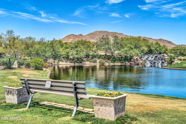 view of home's community with a water and mountain view and a lawn