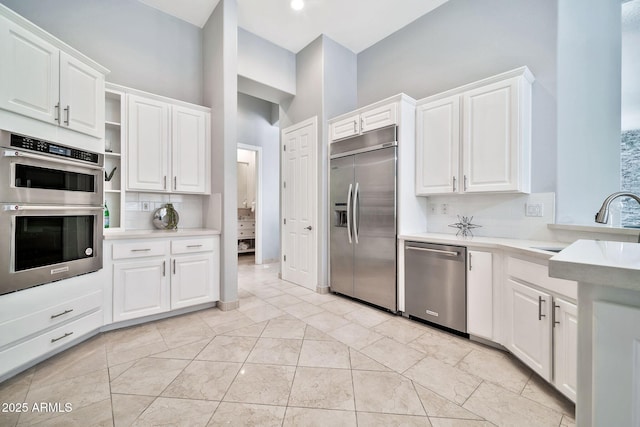 kitchen featuring a sink, white cabinets, light countertops, appliances with stainless steel finishes, and tasteful backsplash