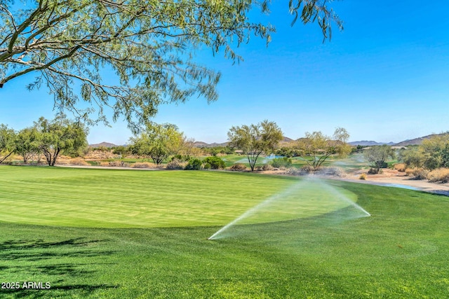 surrounding community with view of golf course, a mountain view, and a lawn