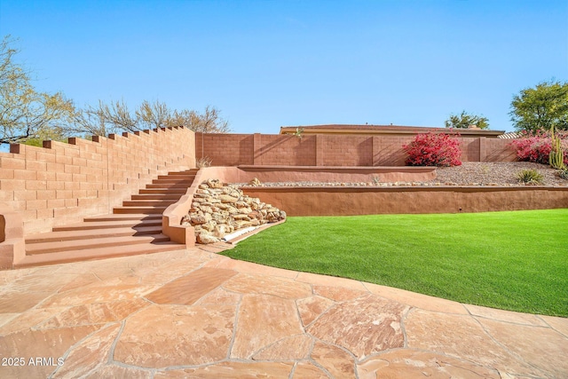 view of yard with a fenced backyard, stairway, and a patio