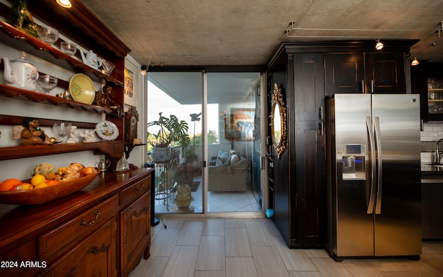 kitchen featuring dark brown cabinetry, stainless steel fridge, and expansive windows