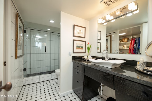 bathroom with tiled shower, tile patterned floors, vanity, and toilet