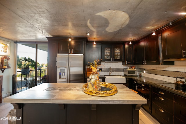 kitchen featuring backsplash, sink, black stovetop, stainless steel fridge, and a kitchen island