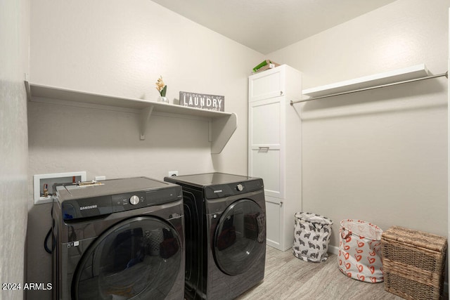 clothes washing area featuring cabinets, washing machine and dryer, and light hardwood / wood-style flooring