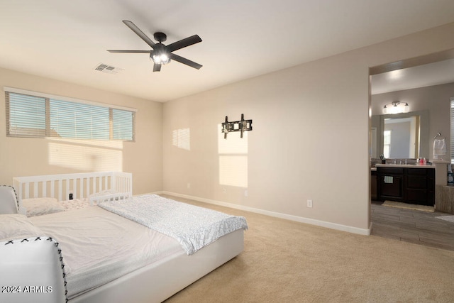 bedroom featuring ceiling fan, light colored carpet, sink, and connected bathroom