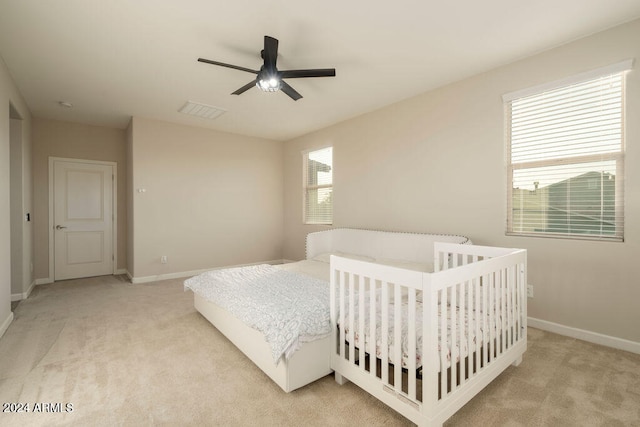 bedroom with multiple windows, ceiling fan, and light carpet