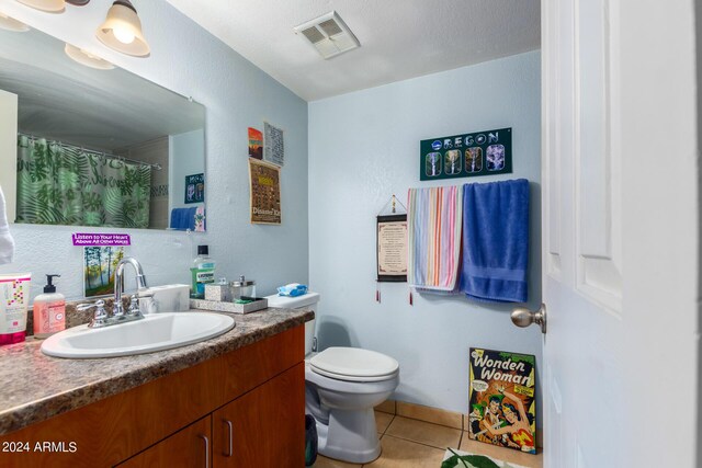 bathroom with vanity, toilet, curtained shower, a textured ceiling, and tile patterned flooring