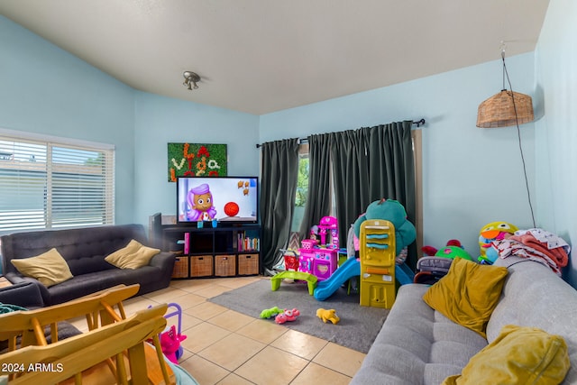 rec room featuring vaulted ceiling, light tile patterned floors, and a healthy amount of sunlight