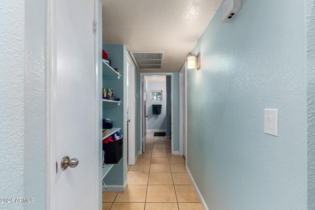 corridor with a textured ceiling and light tile patterned floors