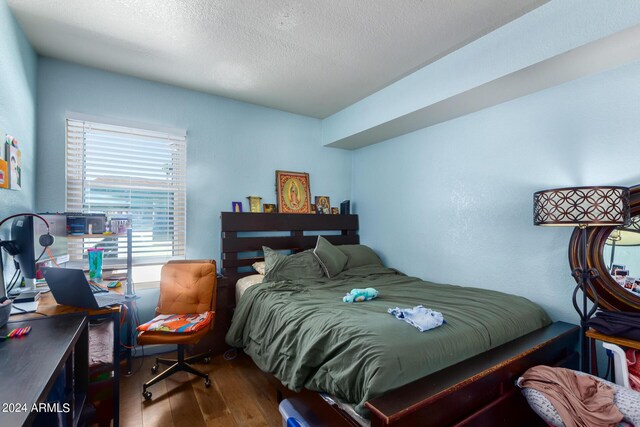 bedroom featuring wood-type flooring and a textured ceiling