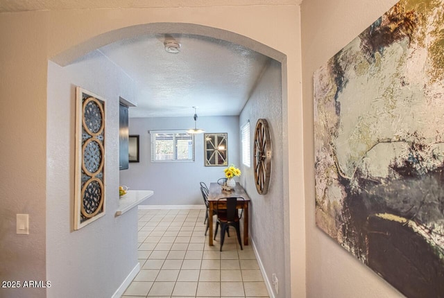 4905 E Horseshoe Ln, Cottonwood, AZ 86326 - hall featuring arched walkways, a textured wall, baseboards, a textured ceiling, and light tile patterned flooring