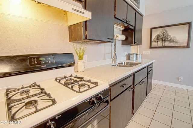 4905 E Horseshoe Ln, Cottonwood, AZ 86326 - kitchen with under cabinet range hood, light tile patterned floors, range with gas cooktop, baseboards, and light countertops