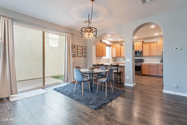 dining space with a notable chandelier, sink, and dark wood-type flooring