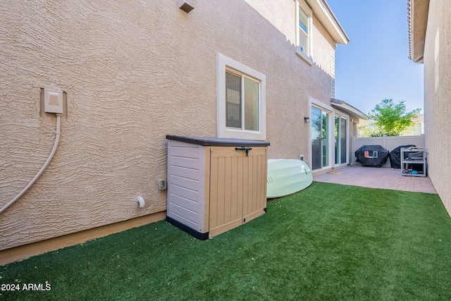 view of side of property featuring a patio area and a lawn