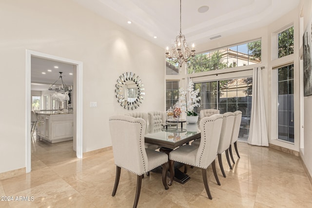 dining space featuring a towering ceiling and a chandelier