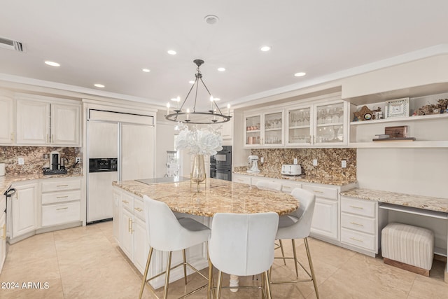 kitchen with a chandelier, light stone counters, a center island, hanging light fixtures, and paneled built in refrigerator