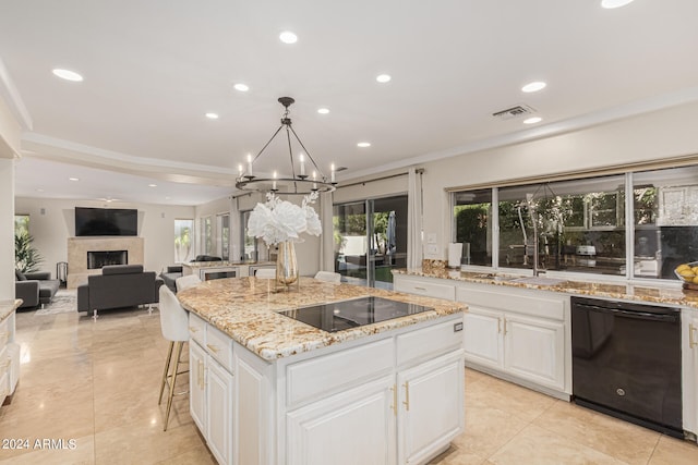 kitchen with white cabinets, black appliances, a center island, a chandelier, and plenty of natural light