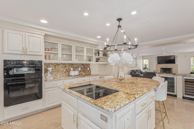 kitchen featuring a chandelier, beverage cooler, white cabinetry, a kitchen island, and black appliances