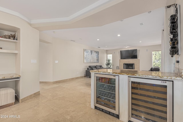 kitchen with beverage cooler, light stone countertops, and light tile patterned flooring