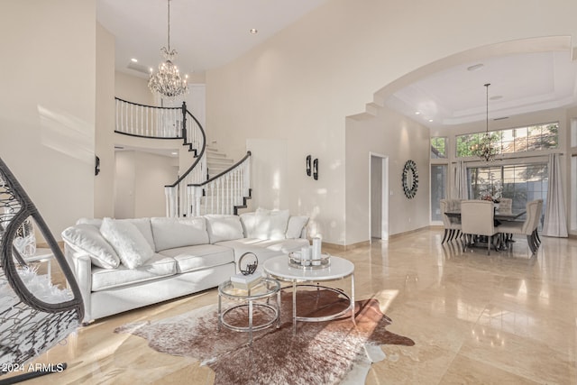 living room featuring an inviting chandelier, a tray ceiling, and a towering ceiling