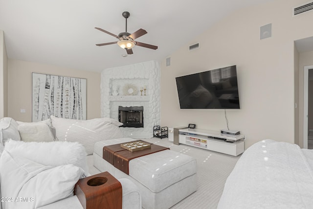 carpeted living room featuring lofted ceiling, ceiling fan, and a stone fireplace