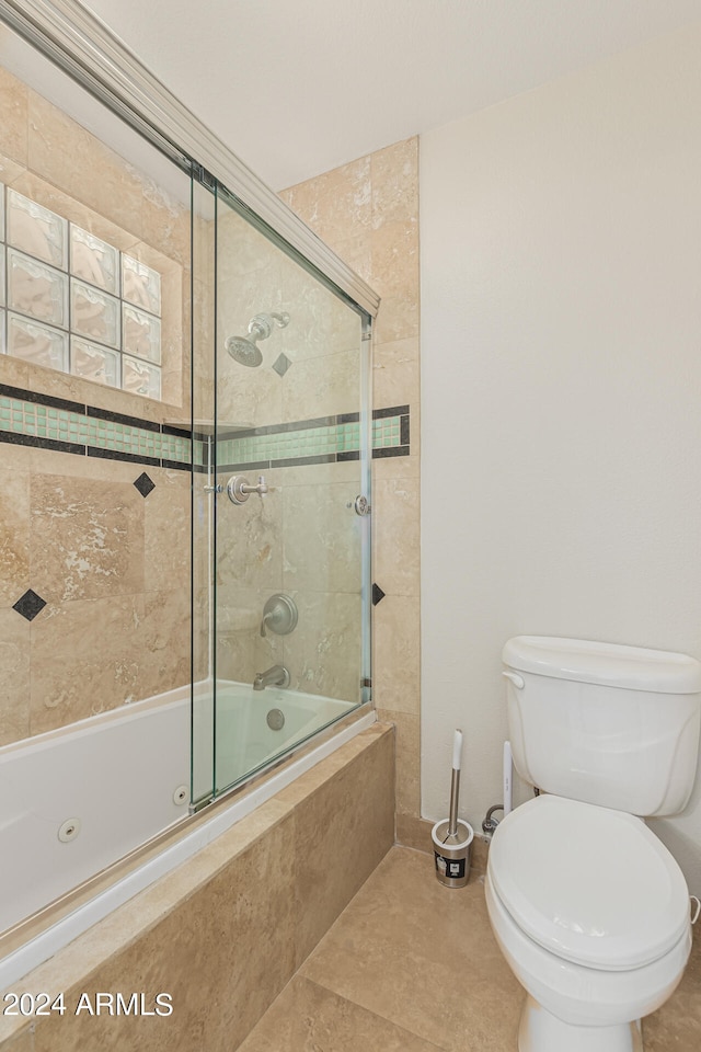 bathroom with tile patterned flooring, combined bath / shower with glass door, and toilet