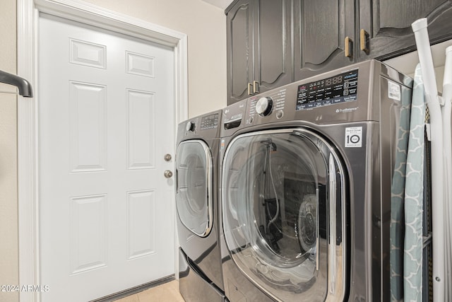 clothes washing area with cabinets, independent washer and dryer, and light tile patterned floors