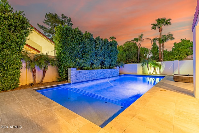 pool at dusk with a patio area