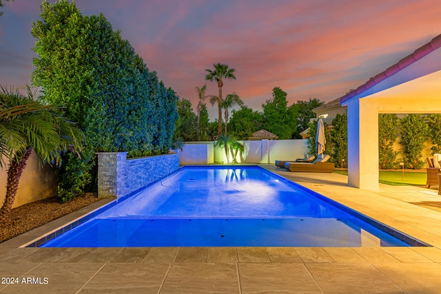 pool at dusk featuring a patio area