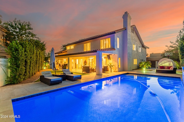 pool at dusk with an outdoor hangout area and a patio area