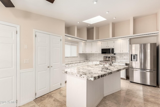 15602 N 19th St, Phoenix, AZ 85022 - kitchen featuring light stone counters, a center island, a skylight, stainless steel appliances, and white cabinets