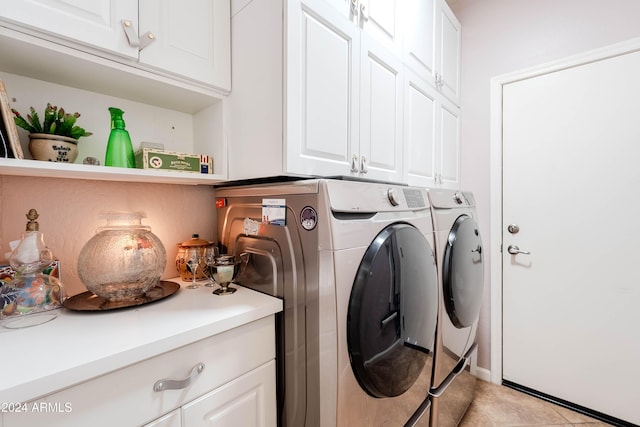 clothes washing area with washer and dryer, light tile patterned floors, and cabinets