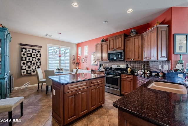 kitchen featuring a center island, sink, decorative backsplash, appliances with stainless steel finishes, and decorative light fixtures