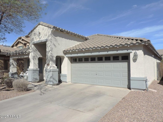 view of front of home featuring an attached garage, driveway, a tile roof, and stucco siding