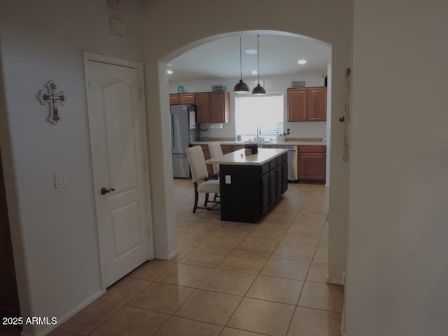 kitchen with arched walkways, a breakfast bar area, light tile patterned floors, stainless steel appliances, and light countertops