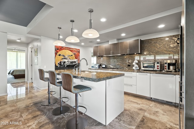 kitchen with a kitchen island with sink, tasteful backsplash, a sink, a toaster, and a breakfast bar