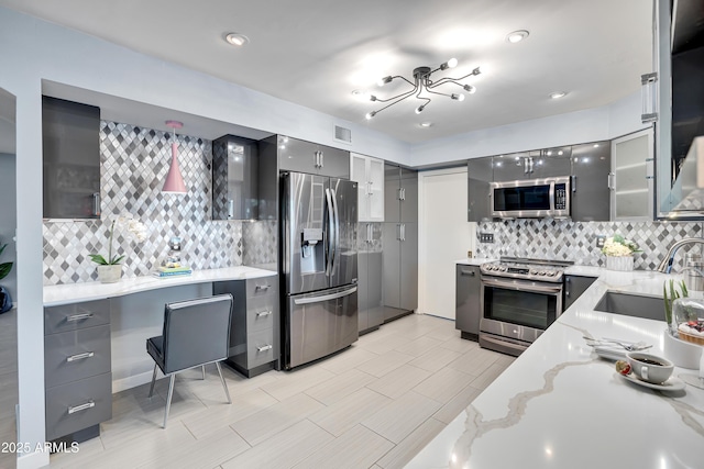 kitchen featuring backsplash, gray cabinets, sink, stainless steel appliances, and light stone counters