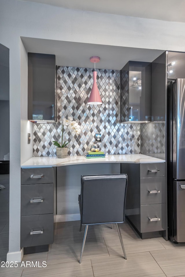 kitchen with backsplash, stainless steel refrigerator, and decorative light fixtures