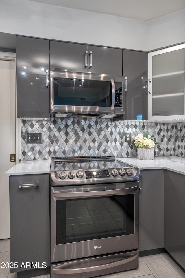 kitchen with appliances with stainless steel finishes, backsplash, and gray cabinets