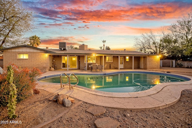 pool at dusk with central AC unit and a patio