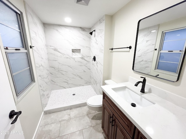 bathroom featuring toilet, vanity, and a tile shower