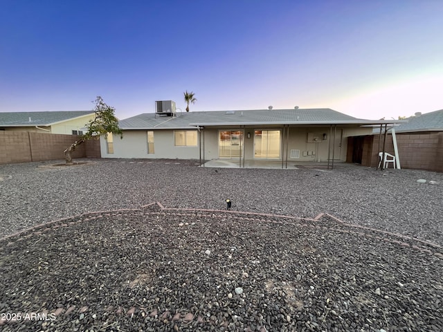 back house at dusk with a patio area and cooling unit