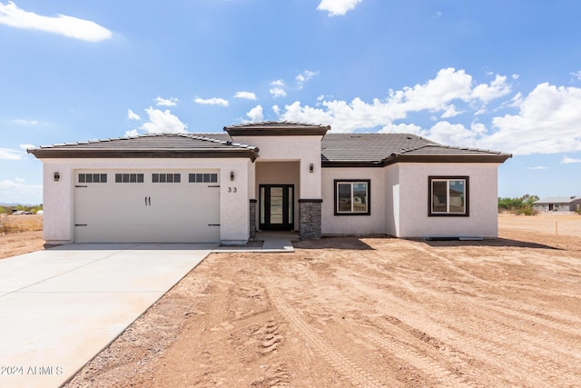 prairie-style home with a garage, concrete driveway, a tiled roof, and stucco siding