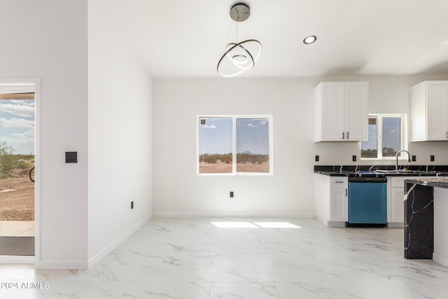 kitchen with white cabinets, dark countertops, dishwashing machine, hanging light fixtures, and marble finish floor