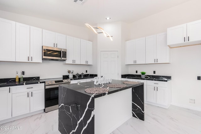 kitchen featuring a center island, white cabinetry, appliances with stainless steel finishes, and light tile patterned floors