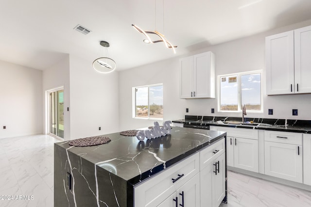 kitchen with light tile patterned floors, sink, hanging light fixtures, and a kitchen island