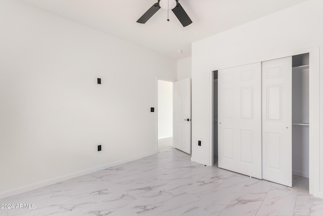 unfurnished bedroom with ceiling fan, marble finish floor, a closet, and baseboards