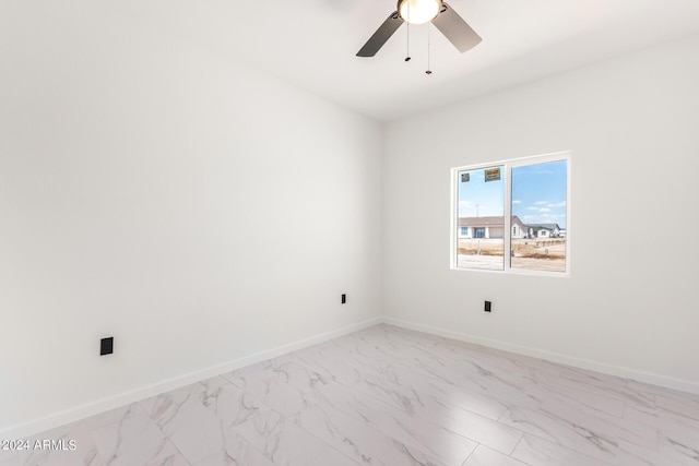 unfurnished room with ceiling fan, marble finish floor, and baseboards