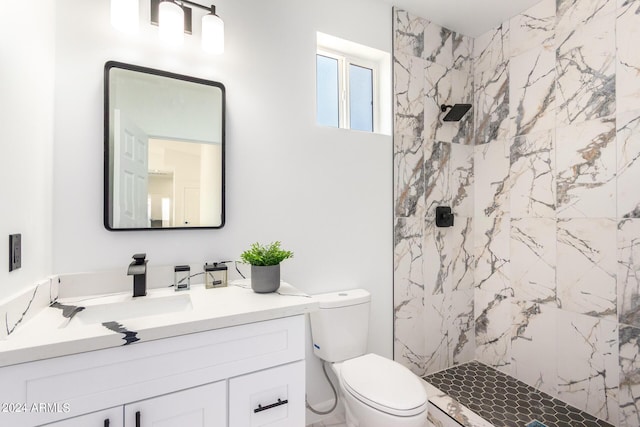 bathroom featuring toilet, a marble finish shower, and vanity